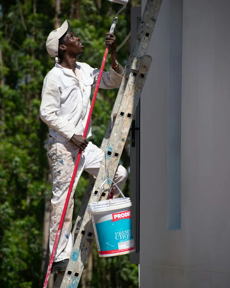 Maler auf der Leiter streicht eine Aussenwand